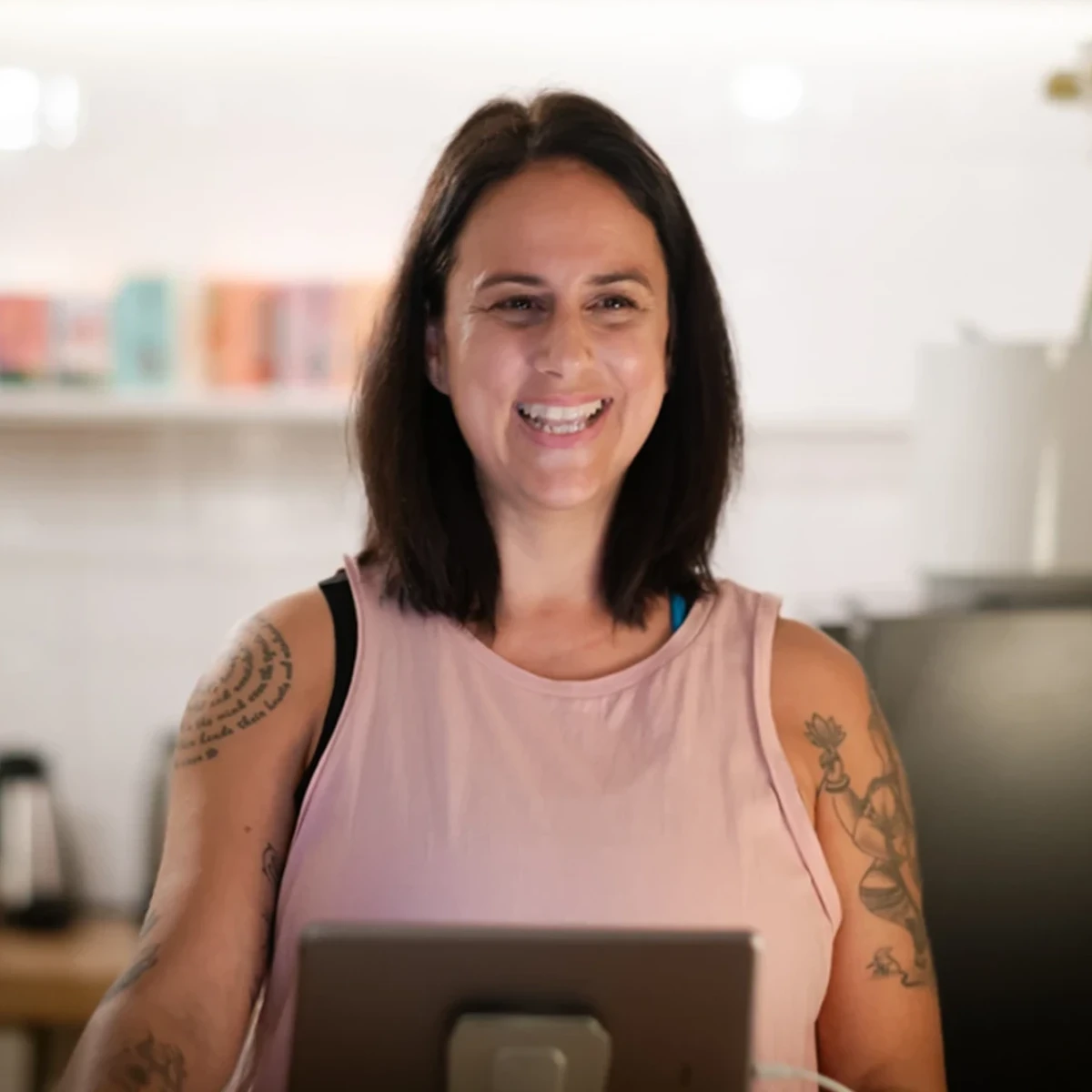 Eine Frau lächelt vor einem Computerbildschirm im Yogastudio, bereit für eine Schnupper-Yogastunde.