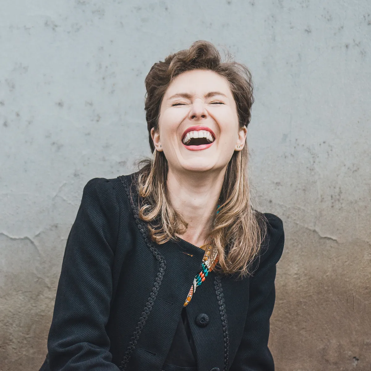 Eine lachende Frau in schwarzer Kleidung strahlt Lebensfreude aus, inspiriert durch die Yoga-Philosophie von YOGALIFE Graz.