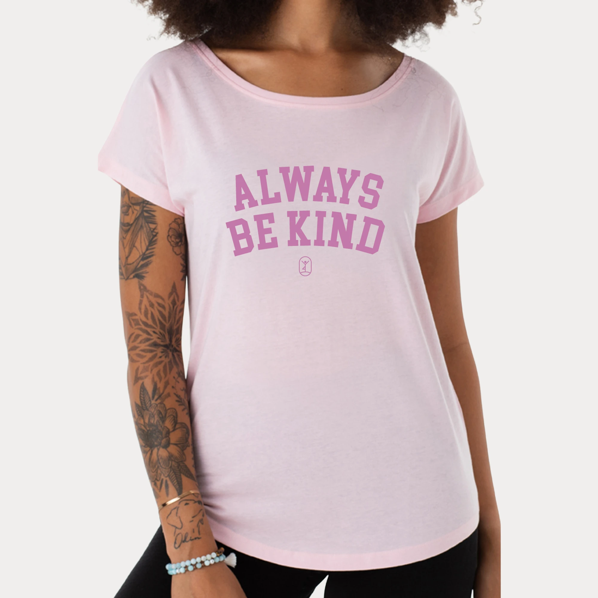 Eine Frau trägt ein rosa Shirt mit dem Schriftzug "Always Be Kind" und strahlt positive Energie aus.