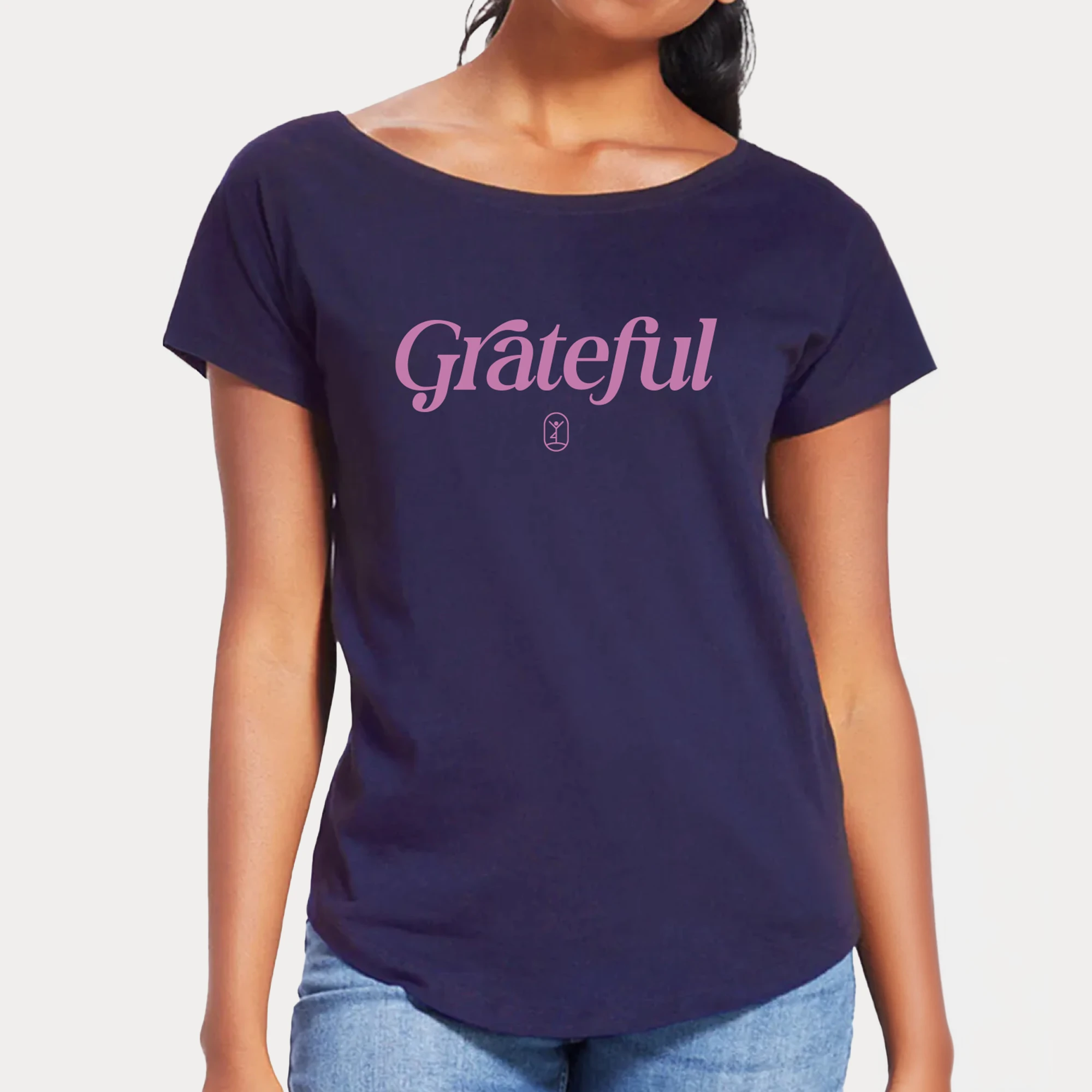 Eine Person trägt ein navyfarbenes Shirt mit dem Schriftzug "Grateful" und lächelt zufrieden in die Kamera.