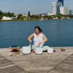 Alex spielt Crystal Bowles am Wasser, umgeben von einer inspirierenden Landschaft.