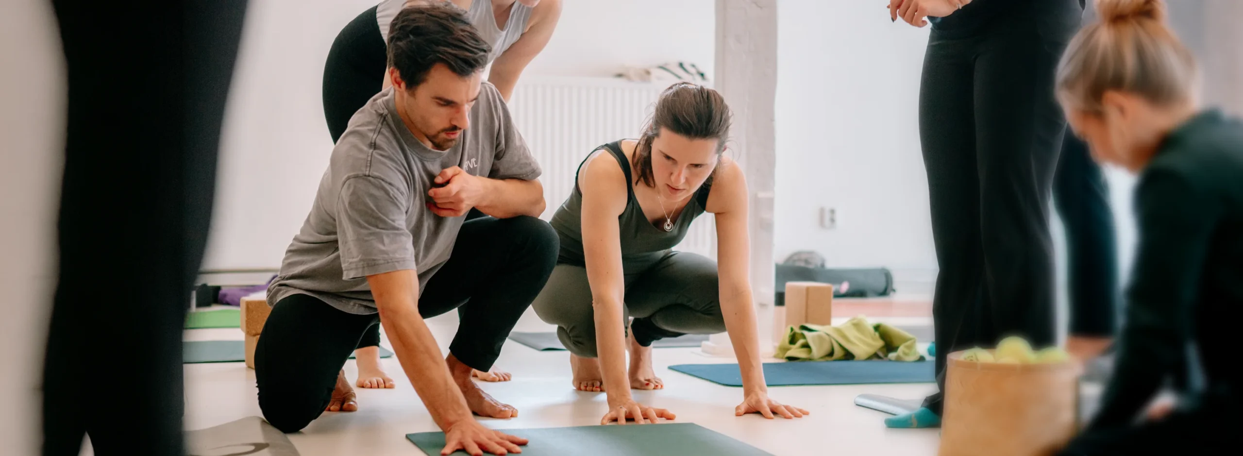 In einem Yogastudio üben Teilnehmer*innen konzentriert auf ihren Matten, inspiriert durch die Atmosphäre von nils_klasse_desktop.