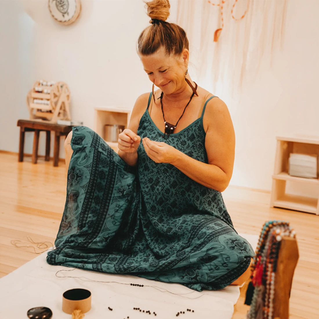 Eine Frau erstellt mit Freude Mala-Perlen im Mala-Knüpfen-Workshop in einem hellen, einladenden Raum.