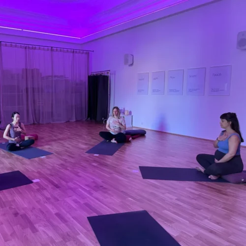 Drei schwangere Frauen üben gemeinsam Yoga im YOGALIFE-Studio, um sich auf die Geburt vorzubereiten.